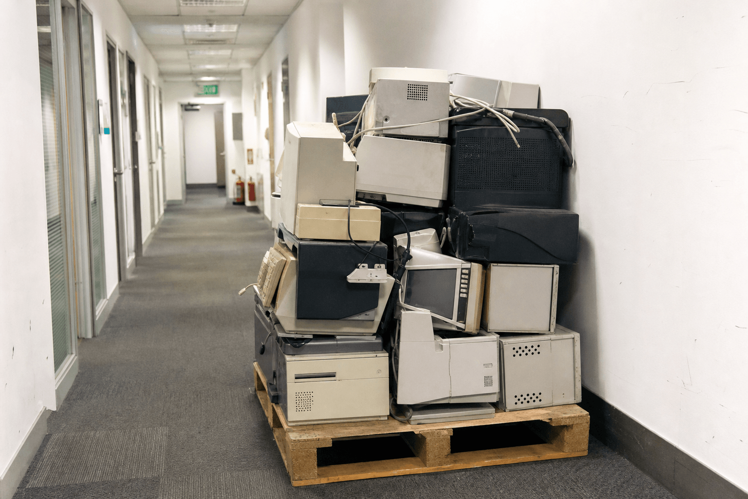 Old office monitors, computers and printers stacked for licensed WEEE collection