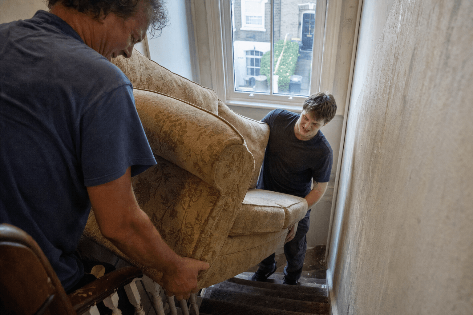 Residents carrying a sofa down stairs before council bulky waste collection