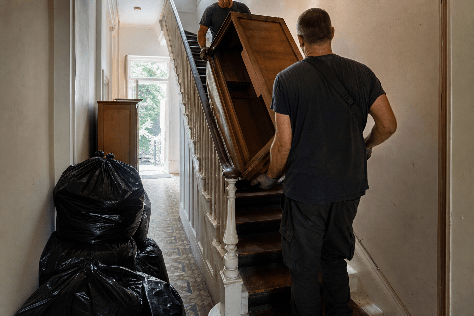 Waste removal team carrying furniture from a London flat during a man and van collection