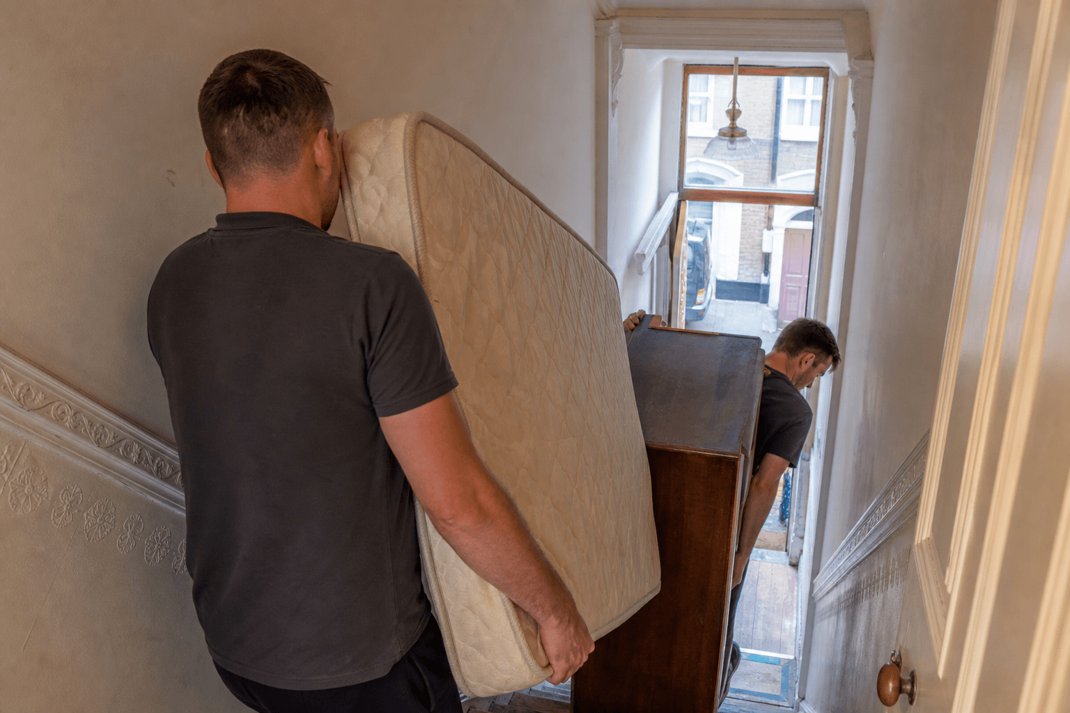 Crew carrying a mattress and wardrobe from a first-floor flat in the Tonsleys, Wandsworth