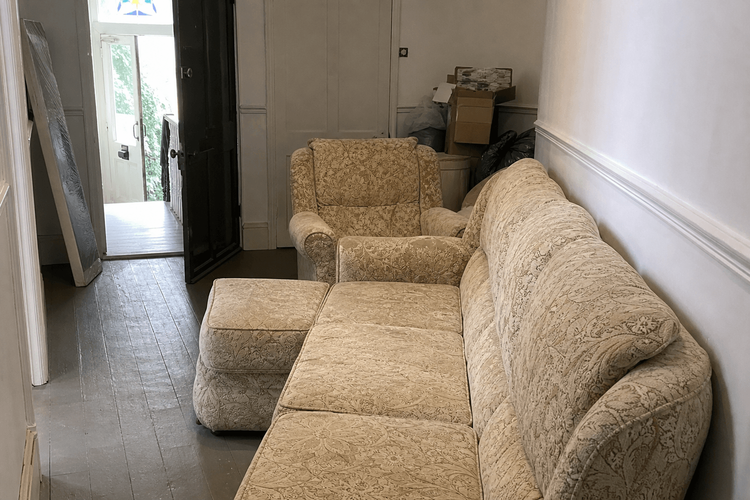 Old sofa and furniture waiting for collection in a London flat hallway